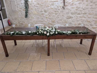 Décoration de table d'honneur classique avec guirlande de sapin, roses blanches, eucalyptus et bougies, mariage hivernal.