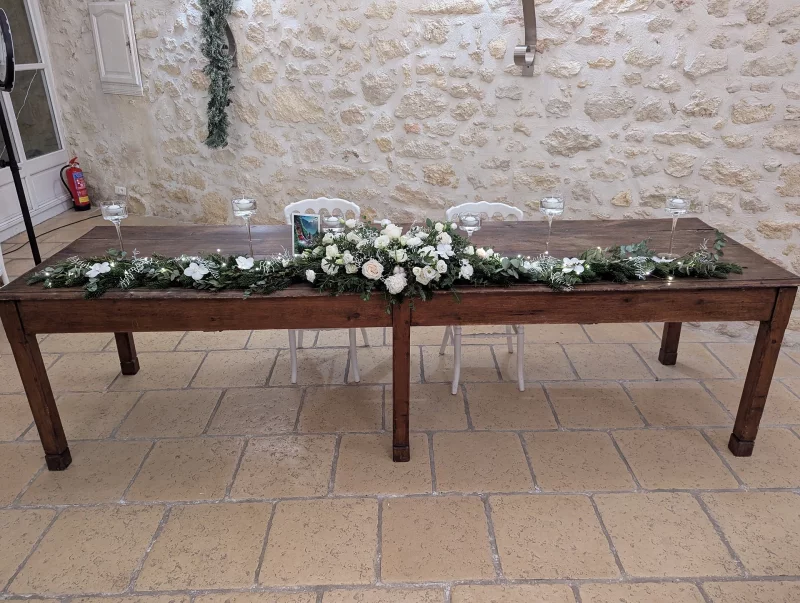 Classic top table decoration with a fir garland, white roses, eucalyptus, and candles for a winter wedding.