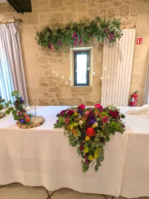 Vue d'ensemble de la table d'honneur avec composition florale et végétalisation suspendue, mariage à Barsac.