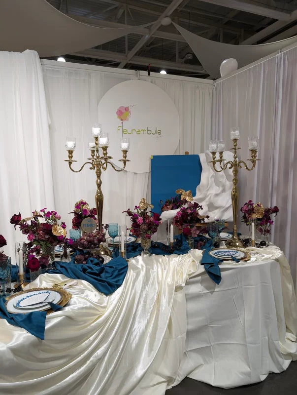 Décoration de table d'honneur classique avec compositions florales bordeaux, orchidées magenta et touches dorées pour un salon du mariage.