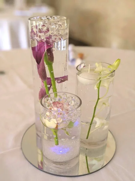 Composition de vases cylindriques centre de table mariage, callas violets, orchidée blanche et fleur rose.