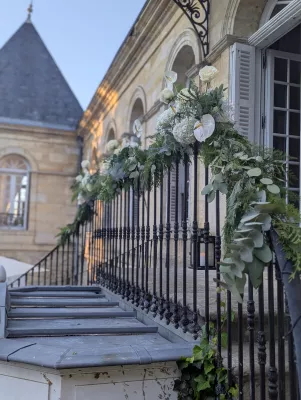 White and green floral arrangements and greenery on the staircase railing of Château des Eyres.