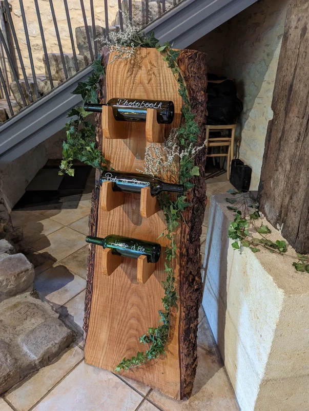 Décoration champêtre de stand en bois avec guirlande de lierre luxuriante et touches de gypsophile blanc pour un mariage.