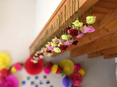 Végétalisation suspendue champêtre pour un mariage, avec des œillets jaunes, roses et rouges créant une ambiance joyeuse et naturelle.