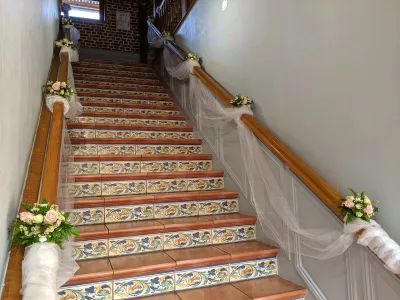 Végétalisation d'escalier de mariage classique avec compositions florales de roses, fougères et tulle blanc.