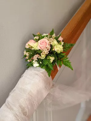 Décoration d'escalier classique pour un mariage estival avec des roses roses et blanches, des fougères luxuriantes.