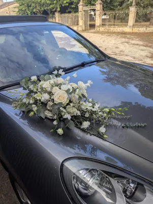 Wedding car floral decoration with cream roses and eucalyptus for a wedding.