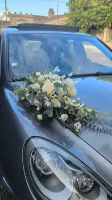 Sophisticated country-style floral decoration for the wedding car with white roses and lisianthus.